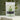 Cardamom Green Tea in a stylish green package with fresh green tea leaves in the background.