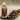 Bottle of clove oil with a wooden scoop of cloves on a textured surface