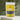Peach Tea in a vibrant yellow package with tea leaves in the background.
