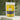 Peach Tea in a vibrant yellow package with tea leaves in the background.